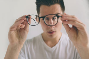 A guy is holding his eyeglasses