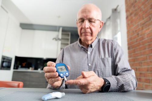 senior man with glucometer checking blood sugar level at home