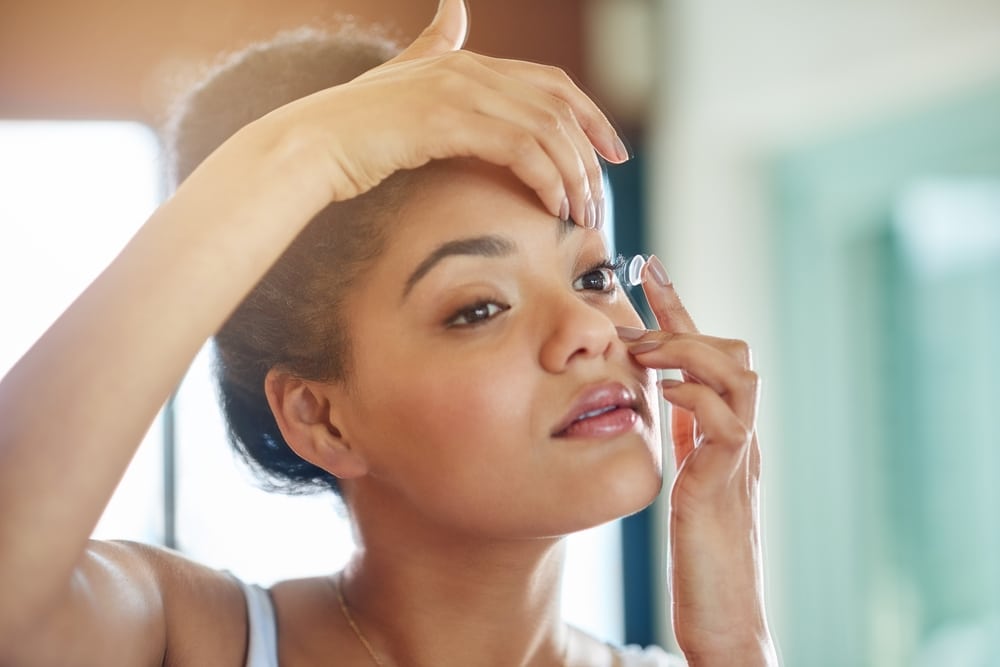 Woman putting contact into her eye