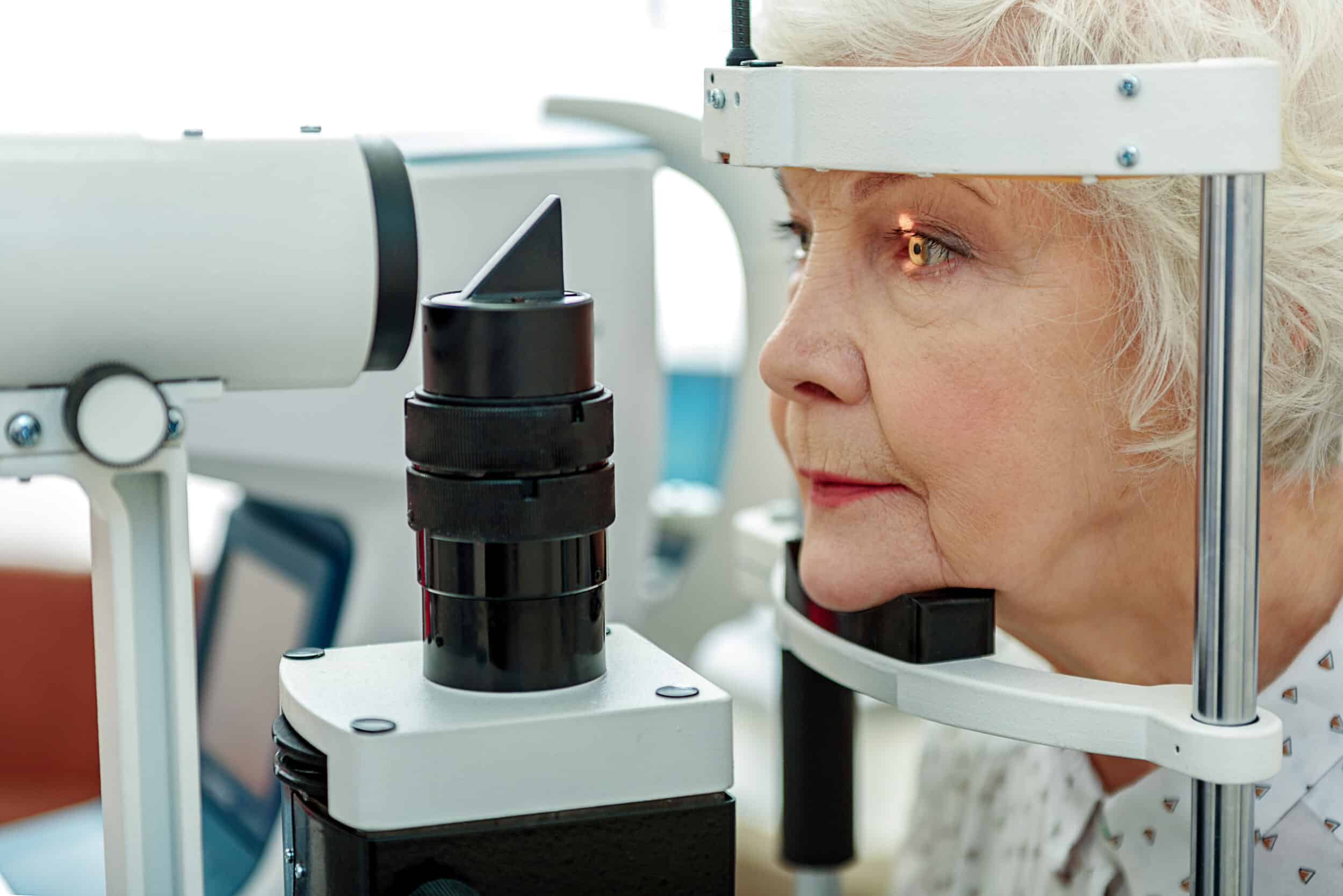 Older woman at eye doctor's, getting eyes examined for cataract surgery