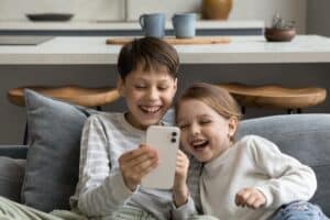 Siblings looking at phone and laughing
